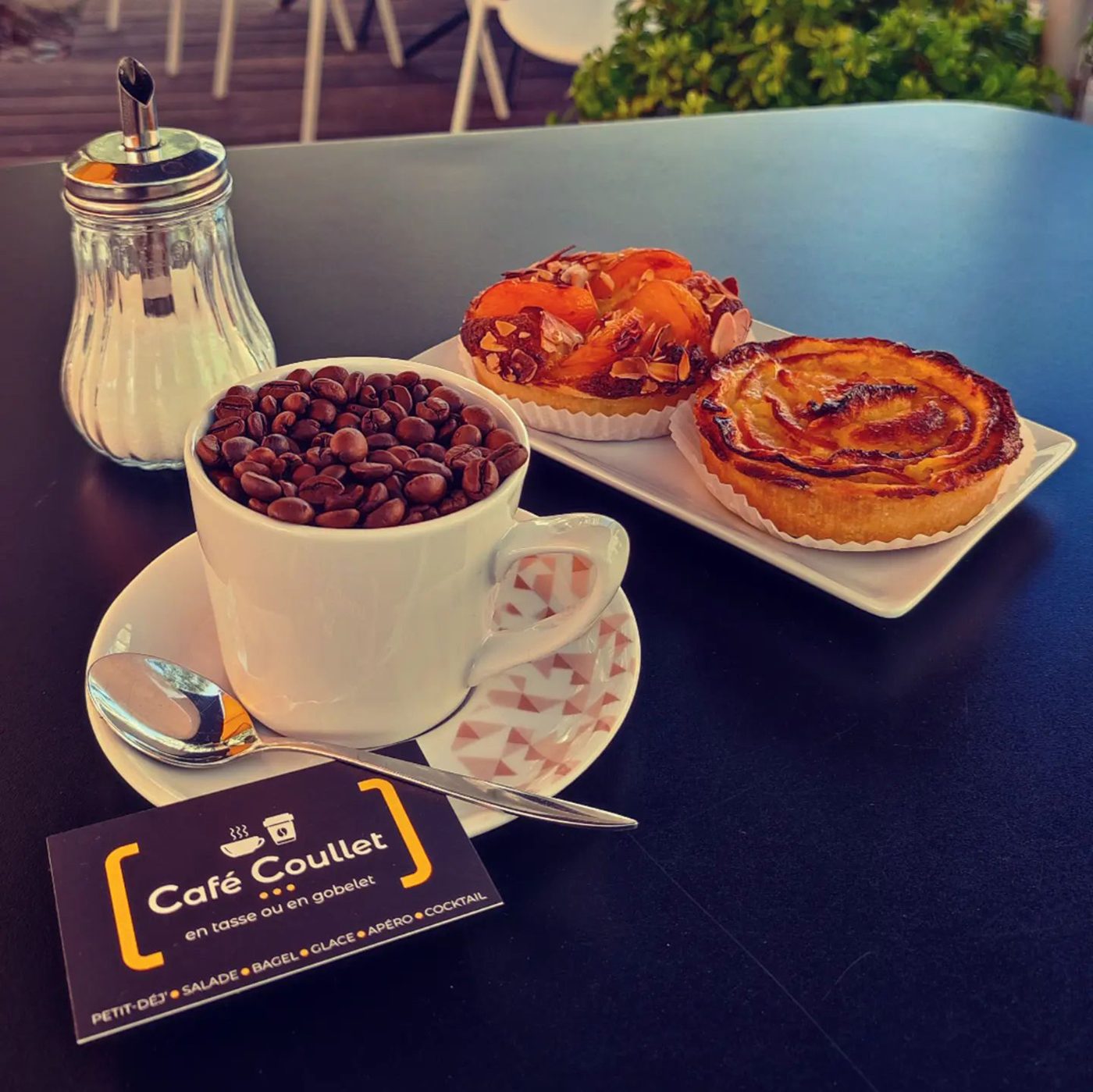 Un café et des viennoiseries sur une table, avec la carte du café