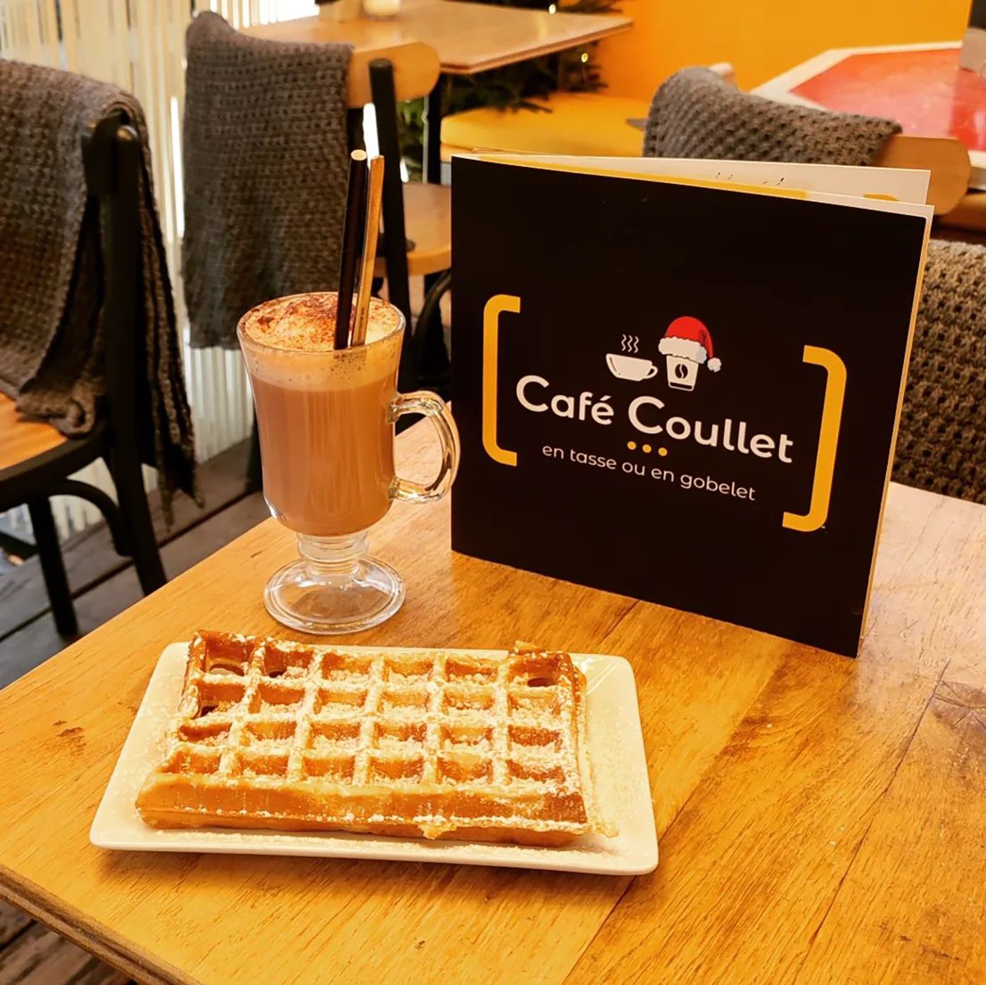 Une boisson chaude nappée de crème et une gaufre sur une table en bois